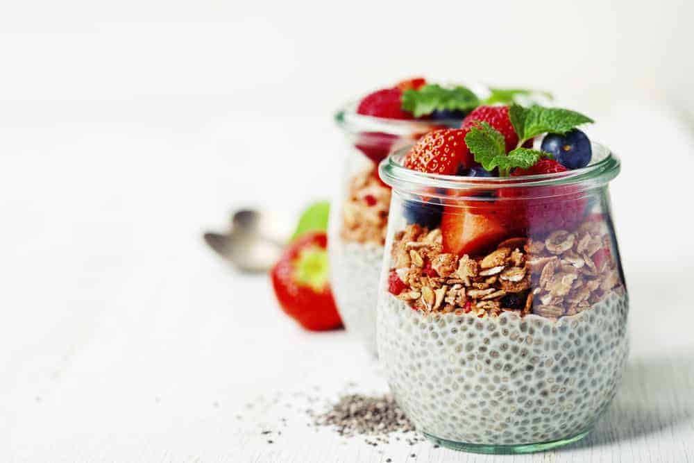 Chia-Pudding mit frischen Erd- und Blaubeeren auf weißem Holztisch
