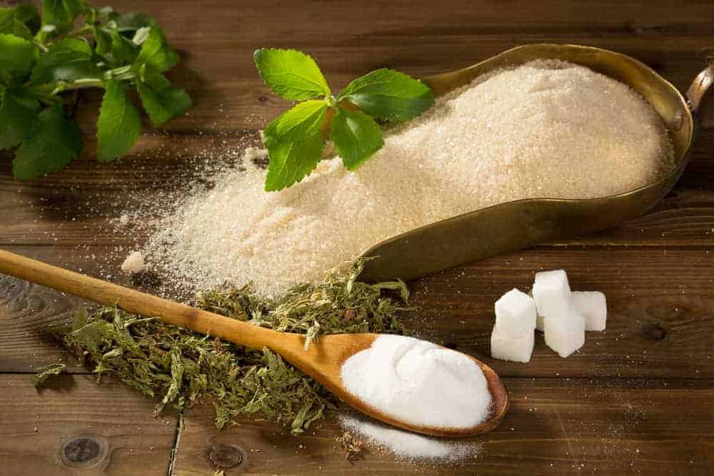 Weißer und brauner Zucker auf Holztisch mit Steviablättern