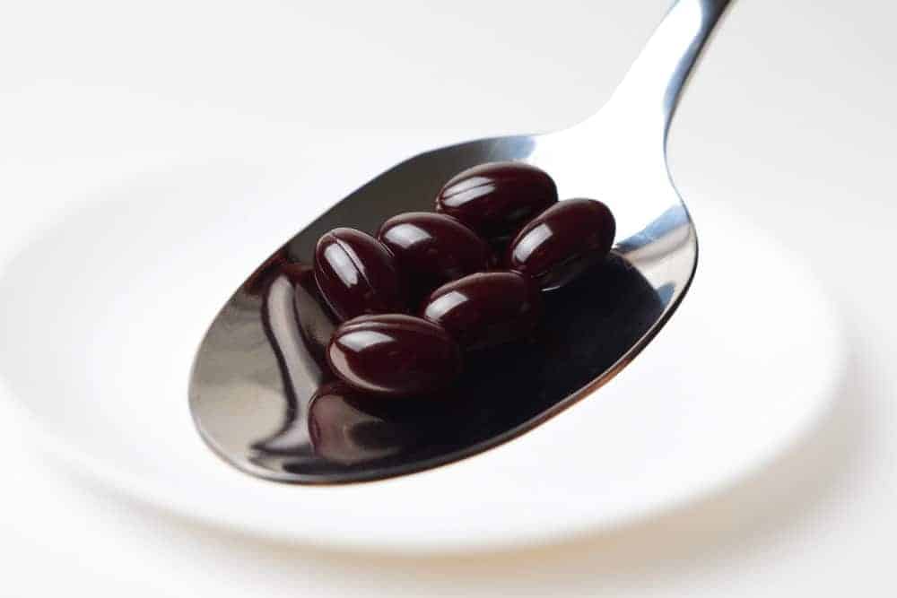 Astaxanthin Kapseln auf einem Löffel