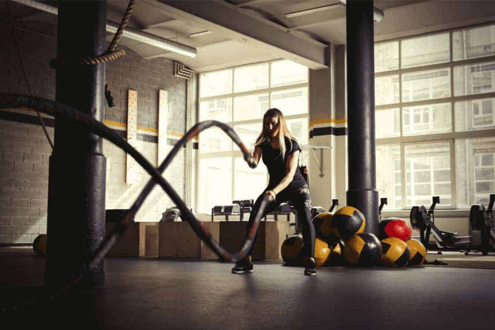 Junge Frau am Battle Rope im Crossfit-Studio