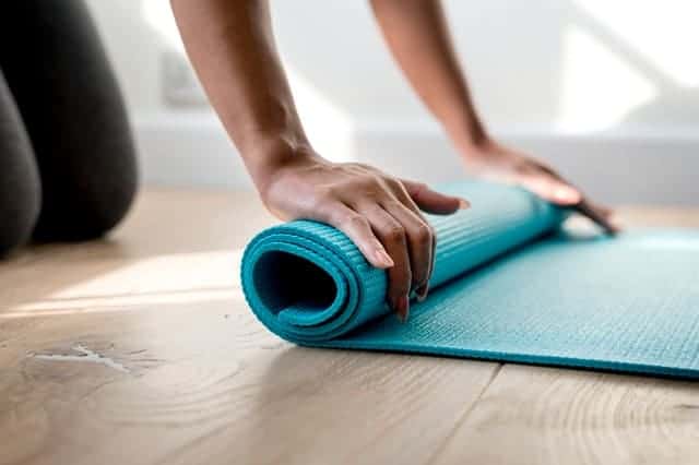 Junge Frau rollt Yogamatte auf