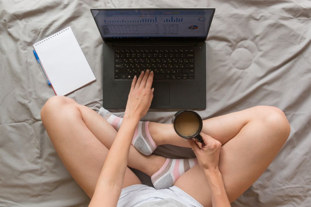 Person vor ihrem Laptop im Bett