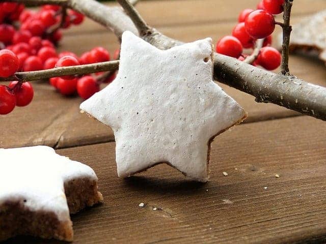 Frisch gebackene Zimtsterne und Holzzweige auf Holztisch