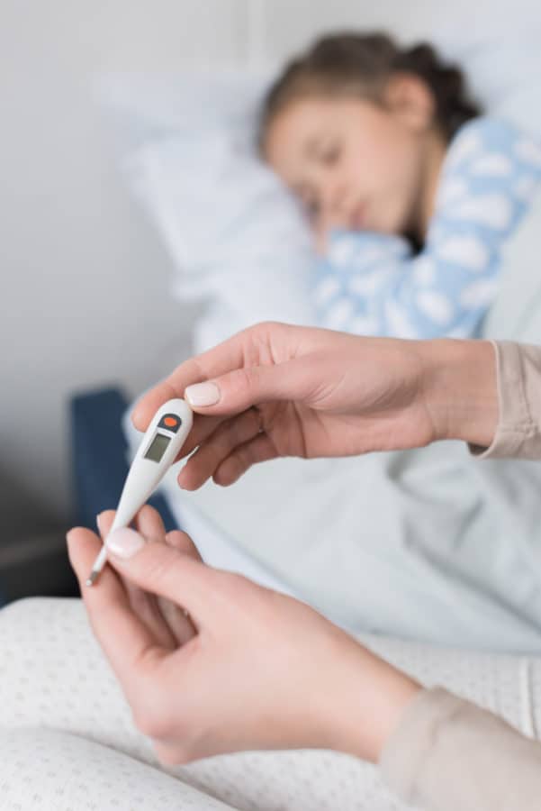 Kind liegt im Bett, Fieberthermomter, Fieber