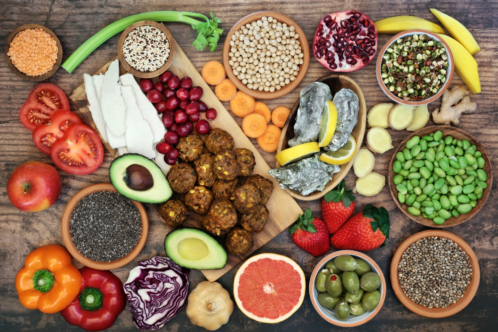 Diverse gesunde Lebensmittel auf einem Tisch, darunter Gem&uuml;se, Obst und Samen