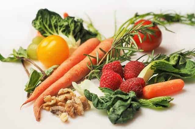 Gemüse, Kräuter, Walnüsse und Himbeeren auf weißem Hintergrund
