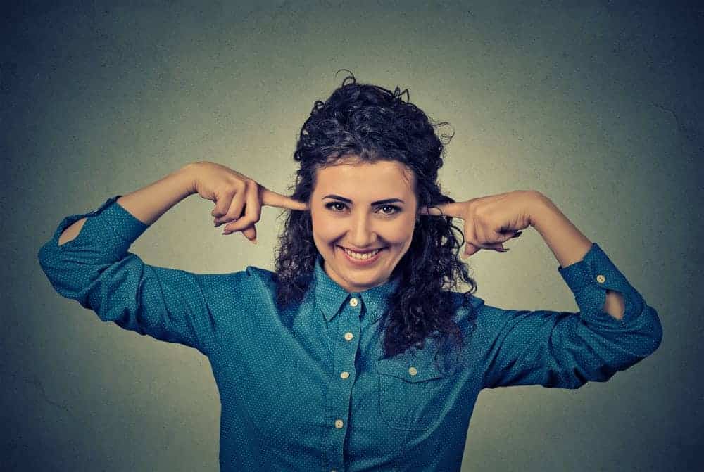 Junge Frau h&auml;lt sich die Ohren zu