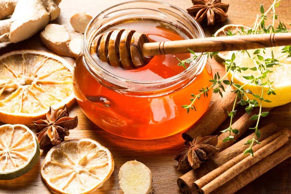 Zimt und Honig neben Orangenscheiben auf einem Tisch