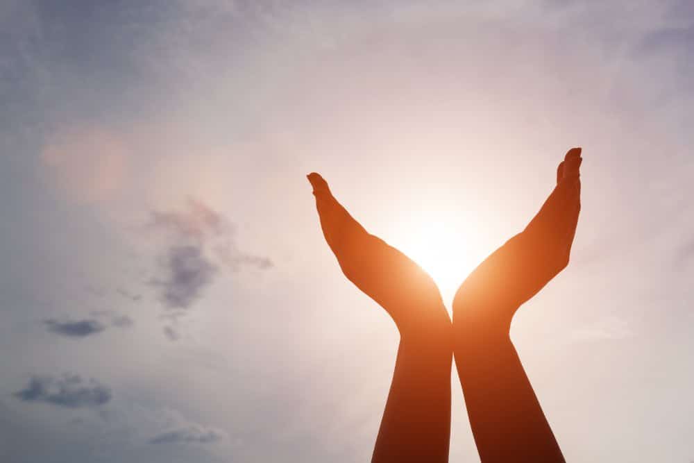 Zwei H&auml;nde zeichnen sich gegen die Sonne ab und scheinen sie zu halten
