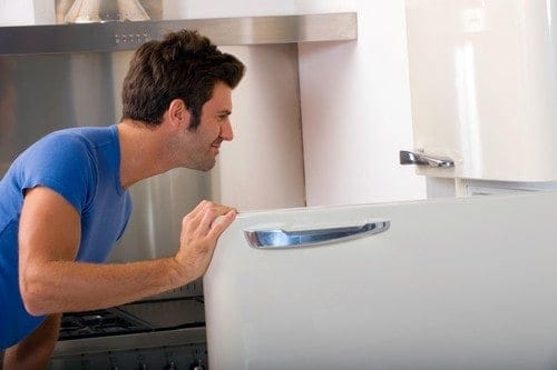 Mann inspiziert geöffneten Kühlschrank