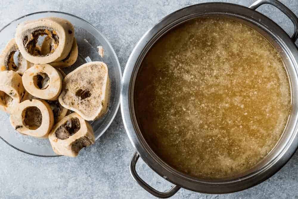 Knochenbr&uuml;he im Kochtopf mit Knochen daneben
